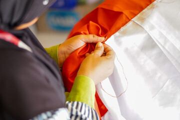 A woman sews the red and white flag, Indonesia's national flag. The theme is celebrating independence on August 17, 1945.