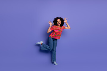 Excited young woman making expressive gestures against a purple background, wearing trendy casual...