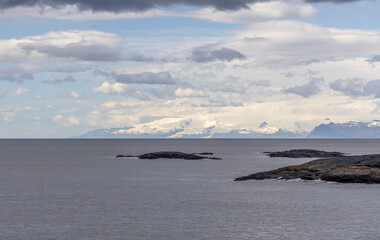 rugged coast and islets at Stokksness, Vestrahorn with snowcapped Vatnajökull glacier in the background, Iceland