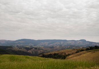 Obraz premium Golden sunset over the rolling green hills of a rural farm in Paraná, Brazil. A peaceful and serene countryside landscape with a rustic fence in the foreground