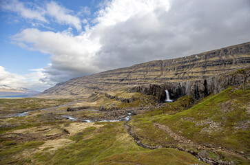 coastal landscape with Folaldafoss waterfall, blue sky and clouds, Berufjardara fjord, East Iceland