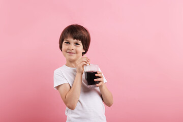 Cute little boy with glass of refreshing soda drink on pink background