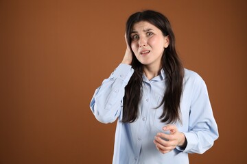 Portrait of shocked woman on brown background, space for text