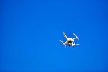 Modern Drone with camera flying on blue sky background.