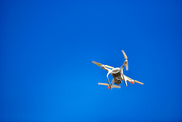 Modern Drone with camera flying on blue sky background.