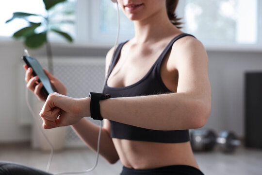 Woman checking fitness tracker during training indoors, closeup