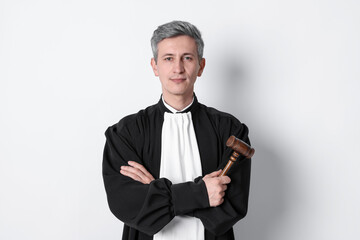 Judge in court dress with mallet on light background