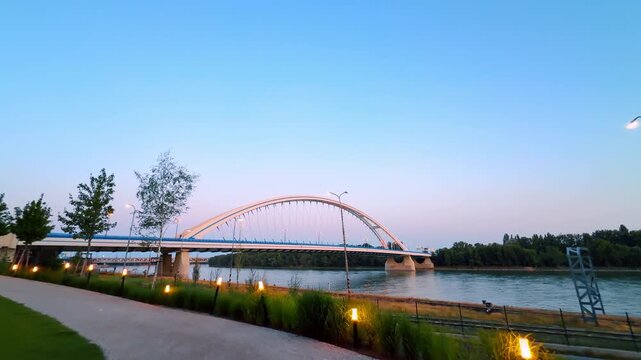 Lights are on in the grass along the road on the river waterfront. Low angle view at the Appolo Bridge in Bratislava, Slovakia.