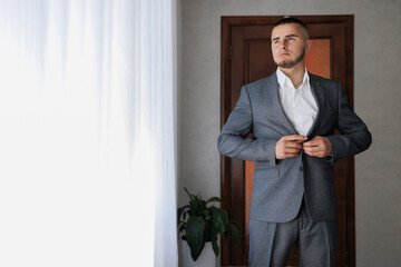 Man adjusting his suit in a well-lit indoor space before an event or occasion