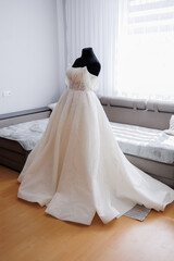Elegant white wedding dress displayed in a cozy interior during daylight hours
