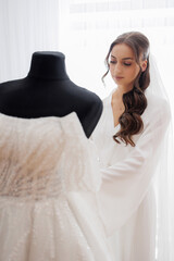 Bride preparing her wedding dress in bright setting before the ceremony begins