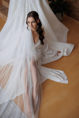 Bridal model poses gracefully in elegant gown with flowing veil indoors near window