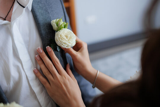 Groom's preparation as bride fastens boutonniere before wedding ceremony