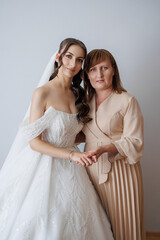 Beautiful bride and mother share a tender moment before the wedding ceremony in a bright setting