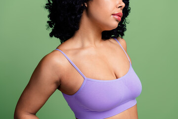 Portrait of a confident woman wearing a lilac top against a green background highlighting natural...