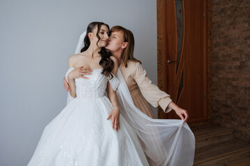 Mother shares a joyful moment with bride in elegant wedding dress before the ceremony