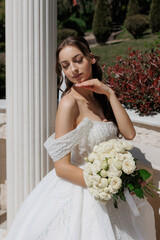 Elegant bride poses with bouquet outdoors at a picturesque venue