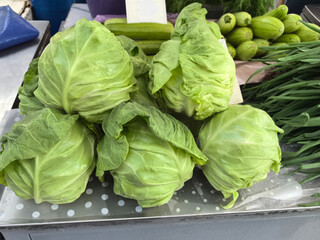 Fresh green cabbages stacked together at a vibrant outdoor market in spring