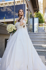 Bride poses gracefully on staircase at outdoor wedding venue during afternoon