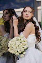 Bride with bouquet gazes thoughtfully at reflection on wedding day