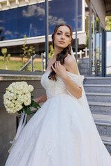 A bridal portrait features a woman in a stunning white dress standing on a staircase