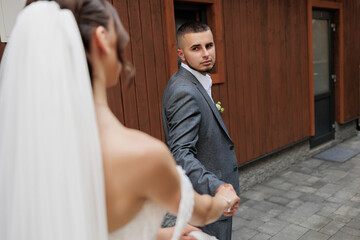 Couple holds hands during their wedding ceremony at a rustic venue in the afternoon light