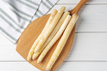 Raw asparagus spears on white wooden table, top view
