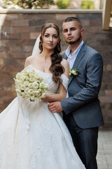 Beautiful wedding couple posing outside with bouquet in hand during sunny celebration day