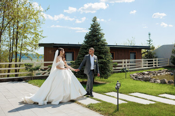 Couple enjoying a sunny wedding day while walking hand in hand in a beautiful outdoor setting