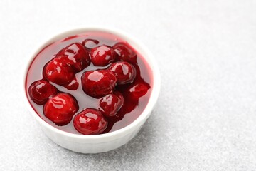 Tasty cherry jam on light table, closeup. Space for text