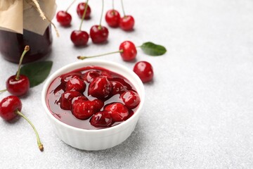 Tasty cherry jam and fresh fruits on light table, closeup. Space for text