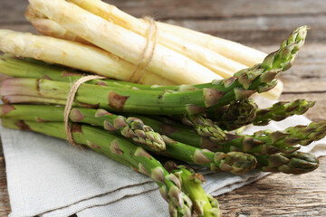 Different raw asparagus spears on wooden table, closeup