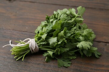 Bunch of fresh aromatic cilantro on wooden table, closeup