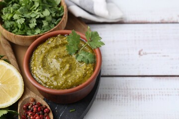 Tasty sauce with cilantro and other ingredients on white wooden table, closeup. Space for text
