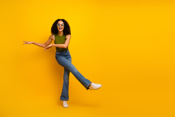 Charming Young Woman in a Trendy Outfit Posing on a Vibrant Yellow Background, Radiating Joy and...