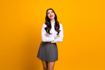 Portrait of a young female in formal attire, posing against a vibrant yellow background, expressing...