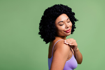 Attractive Woman Embracing Her Natural Beauty in Stylish Purple Attire Against a Green Background