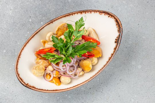 A marinated mushroom salad served with red onion rings, slices of red chili pepper, and fresh parsley on a rustic ceramic plate - Powered by Adobe