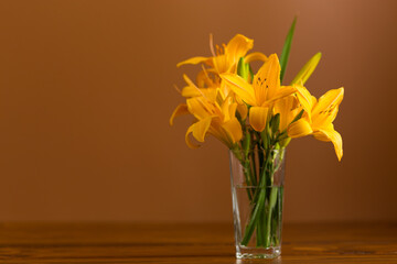 Fresh bouquet of orange lilies on a brown background