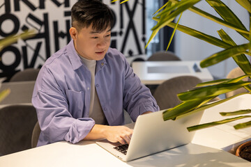 Asian young man working on a laptop in the office