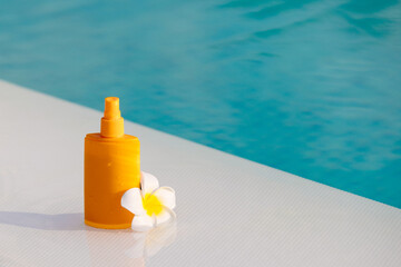 Close-up of a sunscreen spray bottle mockup with a tropical flower nearby. Concept summer skincare...