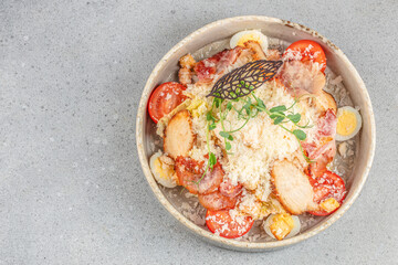 Fresh Caesar salad with grilled chicken breast, cherry tomatoes, crispy bacon, grated cheese, croutons, and quail eggs on a rustic ceramic plate. top view. copy space