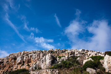 Photo of white rocks against a blue sky with clouds