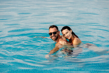 Young beautiful couple relaxing and enjoying vacation in the pool. Concept love, summer leisure,...