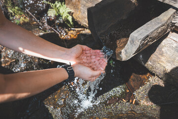 Girl on a hike quenches her thirst with fresh water from a stream originating in the Beskydy...