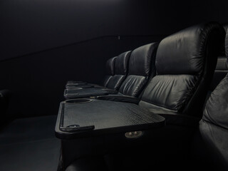 Empty luxurious black leather seats in a dark modern cinema or home theater, featuring individual...