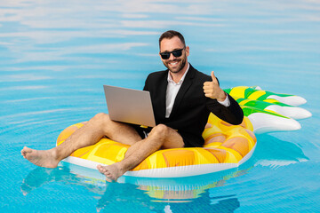 Man in a suit with a laptop showing a thumbs-up gesture. Concept success, remote work and positive...