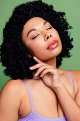 Portrait of a confident young woman against a green background showcasing natural beauty with...