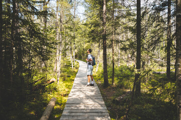 A man is walking on a wooden bridge in a forest