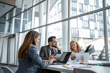 Business people working together on project using laptops in modern office